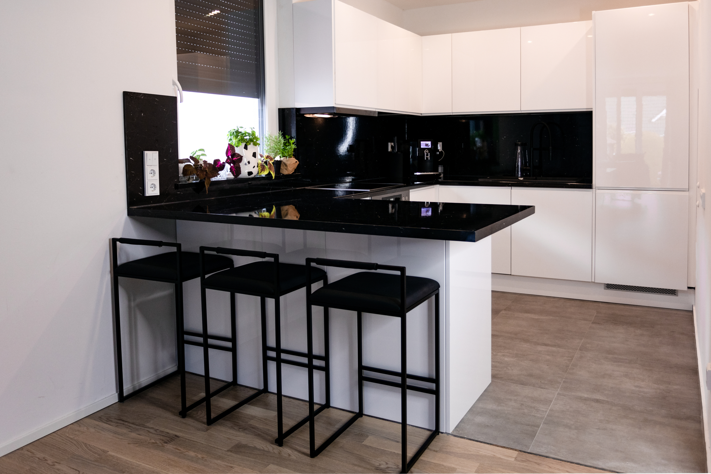 Weiße moderne Küche mit Hochglanz und schwarzen Arbeitsplatten